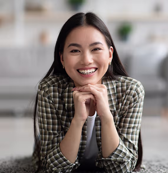 Woman smiling with a defined jawline after buccal fat removal and chin liposuction two months post-op
