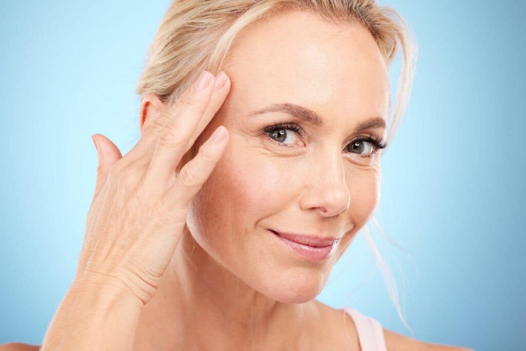 Mature woman touching her smooth skin near the temple, highlighting the effects of regular Botox treatment.