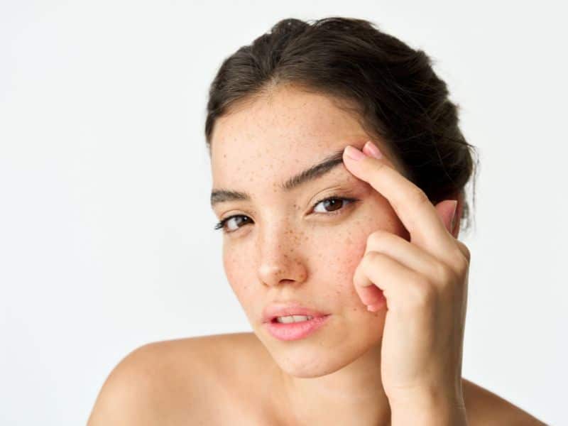 Woman touching her brow, highlighting the lasting effects of an endoscopic brow lift and facial rejuvenation.