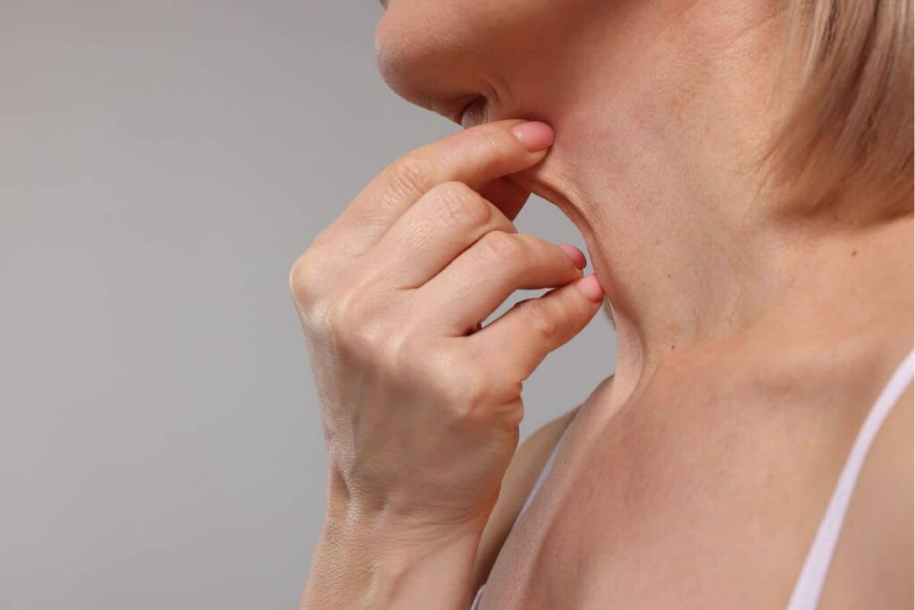 Woman pinching loose skin on her neck, assessing candidacy for a deep neck lift surgery
