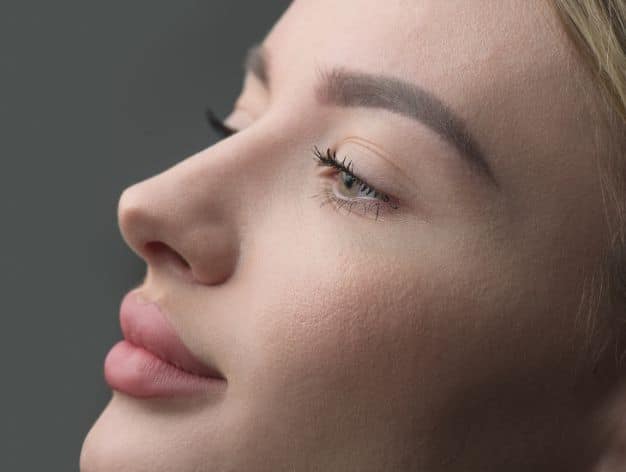 Close-up of a woman's smooth nose and skin, showcasing the effects of laser therapy and topical treatments.