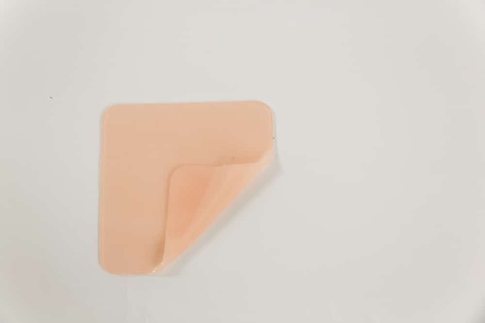 A beige silicone scar tape with a slightly peeled corner on a white background.
