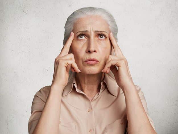 Mature woman touching her temples with a concerned expression, highlighting wrinkles and potential treatments.
